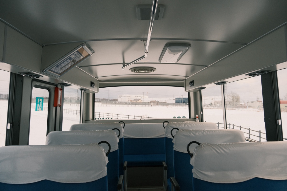 Empty shuttle bus with blue seats looking out at a snowy landscape